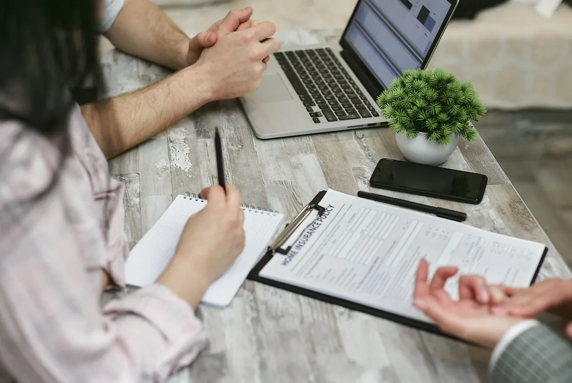 Deux professionnels de l'assurance etudiant une police habitation sur ordinateur, vocabulaire anglais de la souscription