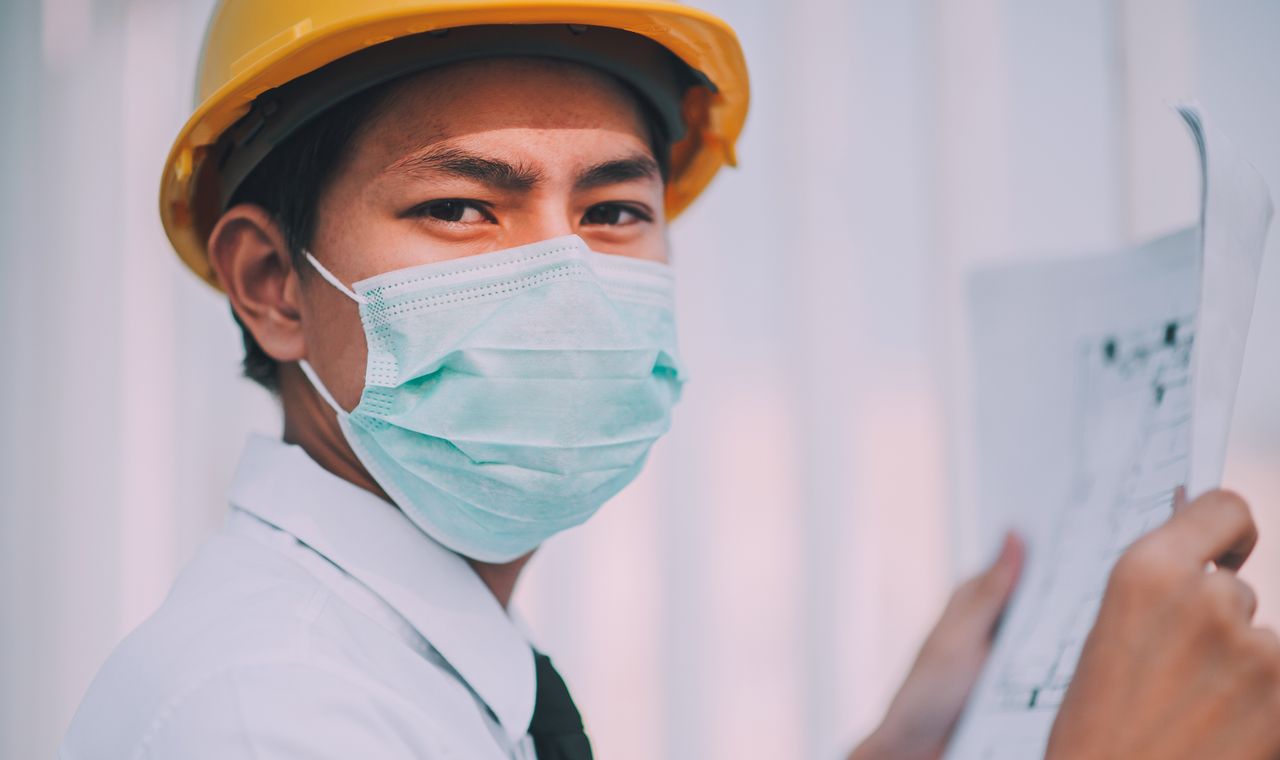 Ingénieur en casque de chantier examinant des plans sur un chantier de construction, formation anglais BTP Cabinet Action