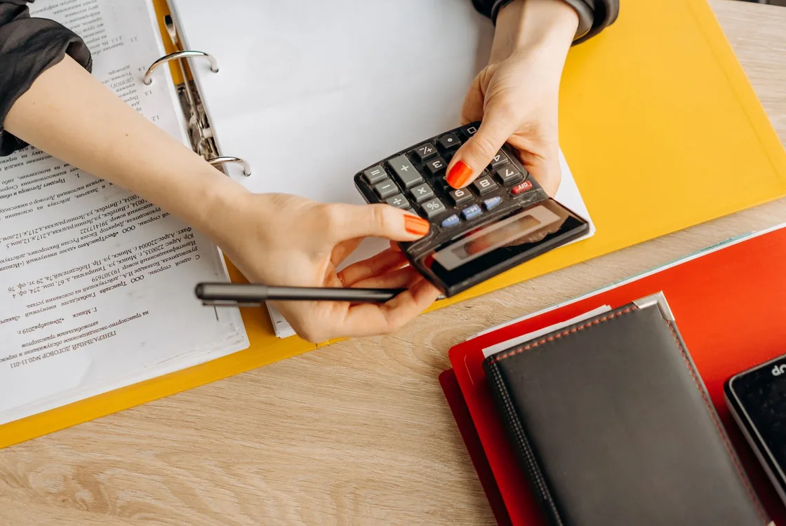 Mains saisissant des ecritures a la calculatrice sur un classeur, lexique anglais de la cloture comptable