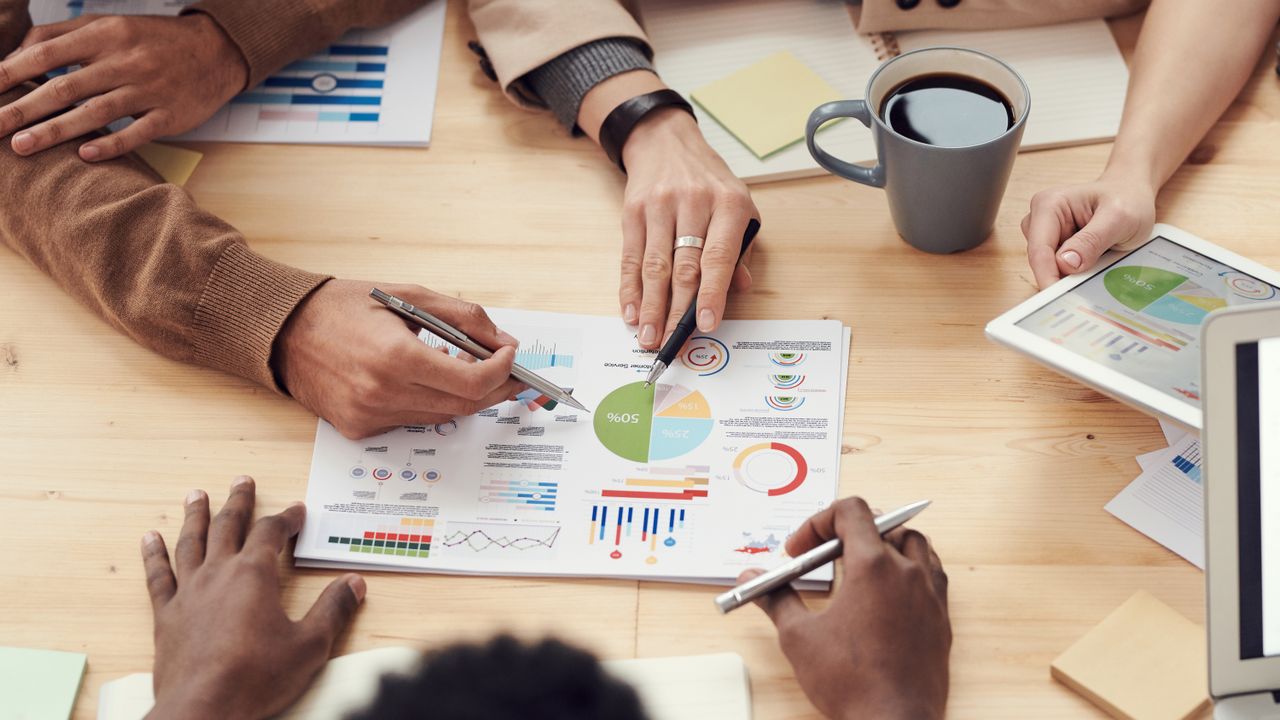 Tableaux de bord financiers, graphiques et tablette lors d'une réunion d'analyse, mise en situation d'anglais financier