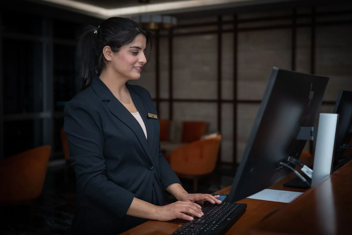 Receptionniste d'hotel enregistrant une reservation a son poste, formation anglais hotellerie Cabinet Action