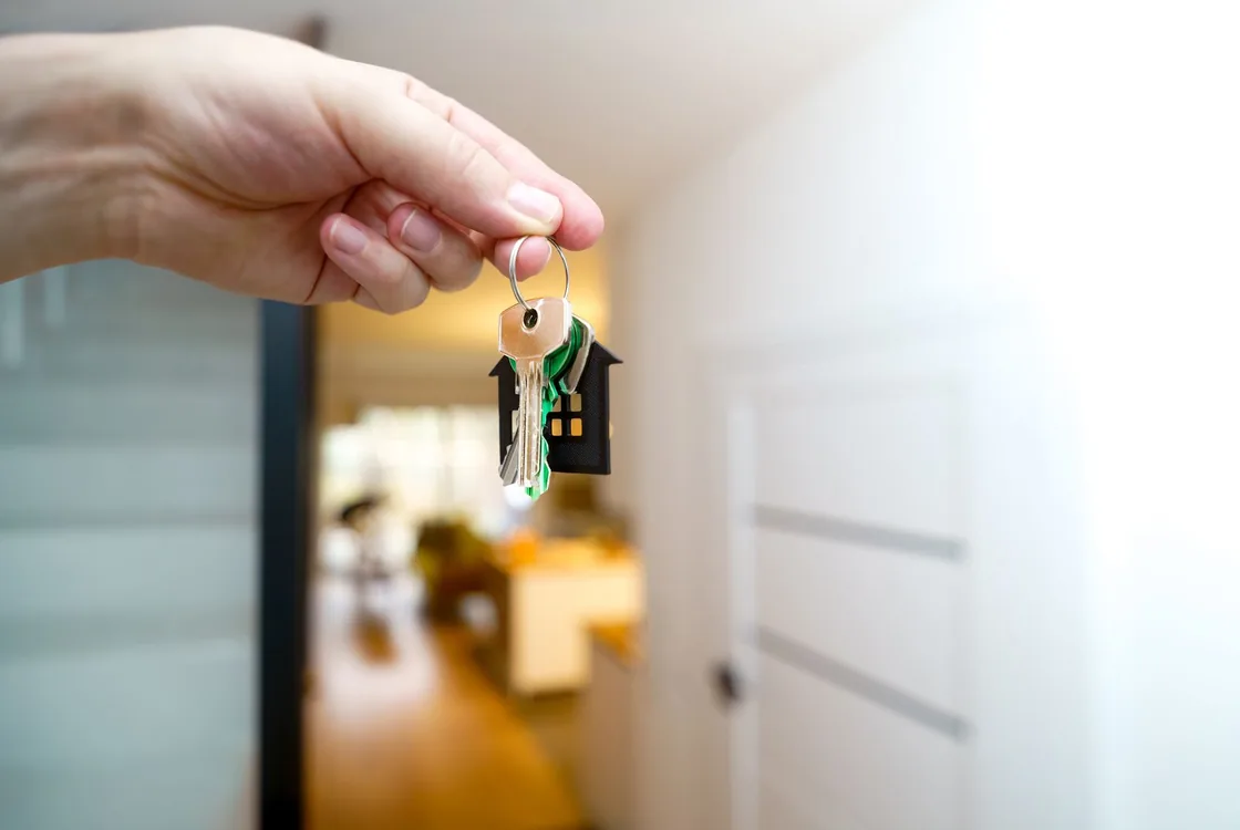 Cles d'un logement neuf tenues devant l'entree, vocabulaire anglais de la transaction immobiliere