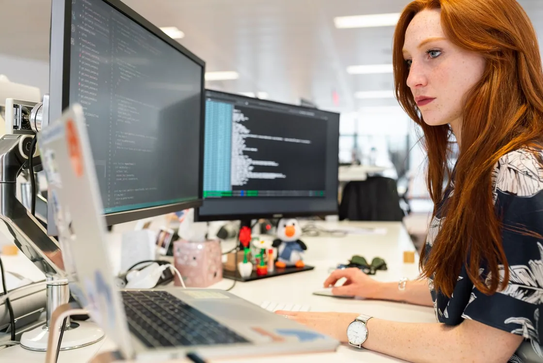 Developpeuse ecrivant du code sur double ecran, formation anglais informatique Cabinet Action