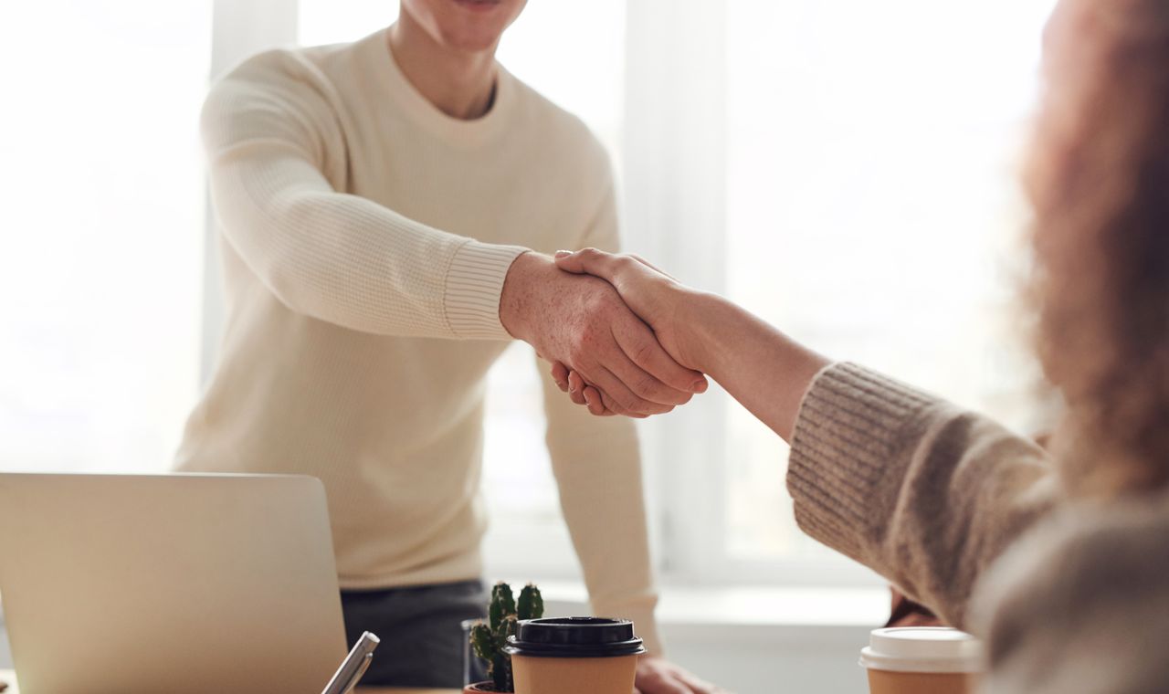 Recruteur et candidat se serrant la main lors d'un entretien d'embauche en entreprise, formation anglais RH Cabinet Action